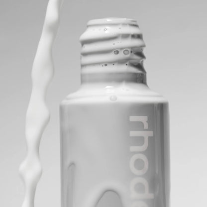 White bottle with 'rhode' branding on a gray background